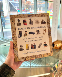 A white hand holding a copy of “Born in Cambridge” by Karen Weintraub and Michael Kuchta