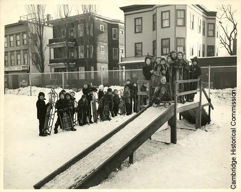 Black and white photo of children sledding down a ramp