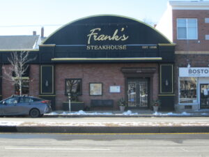 Street level view of a brick building with arched second floor that reads "Frank's Steakhouse"