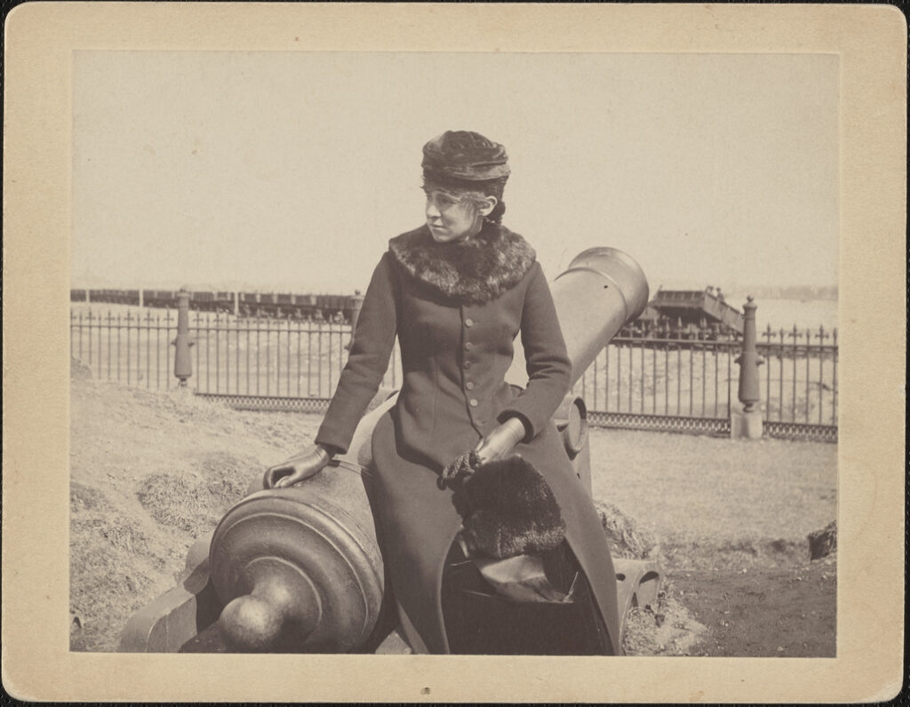 Marian Buckingham sitting on a cannon at Fort Washington commanding the Charles River