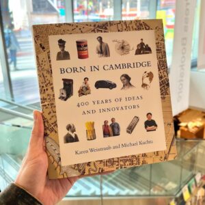 A white hand holding a copy of “Born in Cambridge” by Karen Weintraub and Michael Kuchta