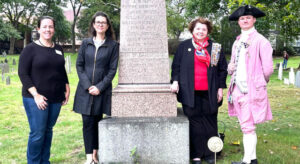 History Cambridge executive director Marieke Van Damme, second from left, and program manager Beth Folsom, left, at the Oct. 6 installation of a marker at the grave of John Hicks in the Old Burying Ground in Cambridge with representatives from the Daughters of the American Revolution and the Boston Tea Party Ships & Museum.