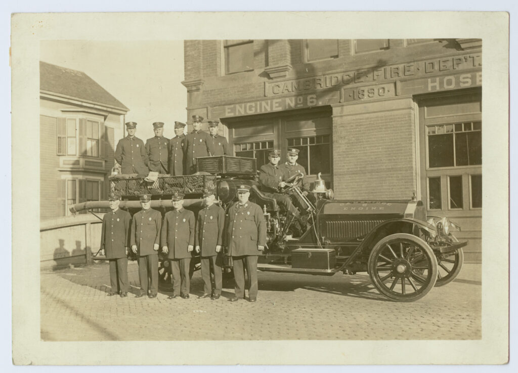 Cambridge Fire Department, Engine #6 (unit in front of truck and station, River Street near Howard) ca. 1921. Now called Rindge School of Technical Arts.