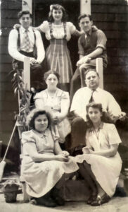 The Karon family on their back porch on Auburn Street in Cambridgeport. Marcine, 15, is at front right, by her younger sister Christine. Her parents, Cleopatra and James Karon are in the middle; at back, from left; are older siblings Angelo, Julia, and Peter.