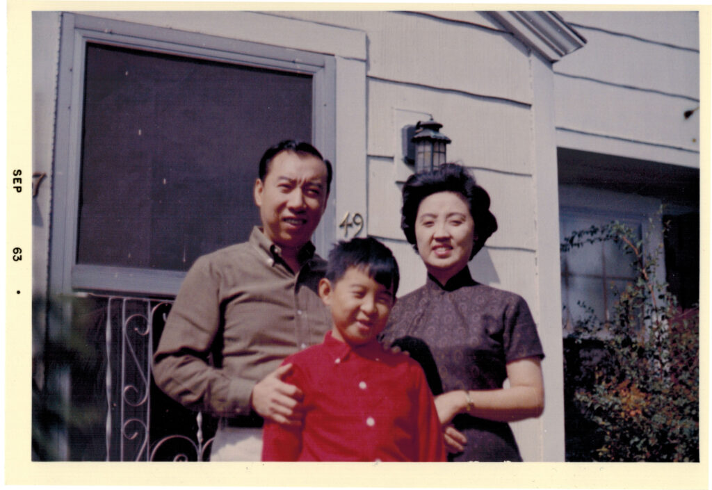 A man, woman, and child standing together int front of a house