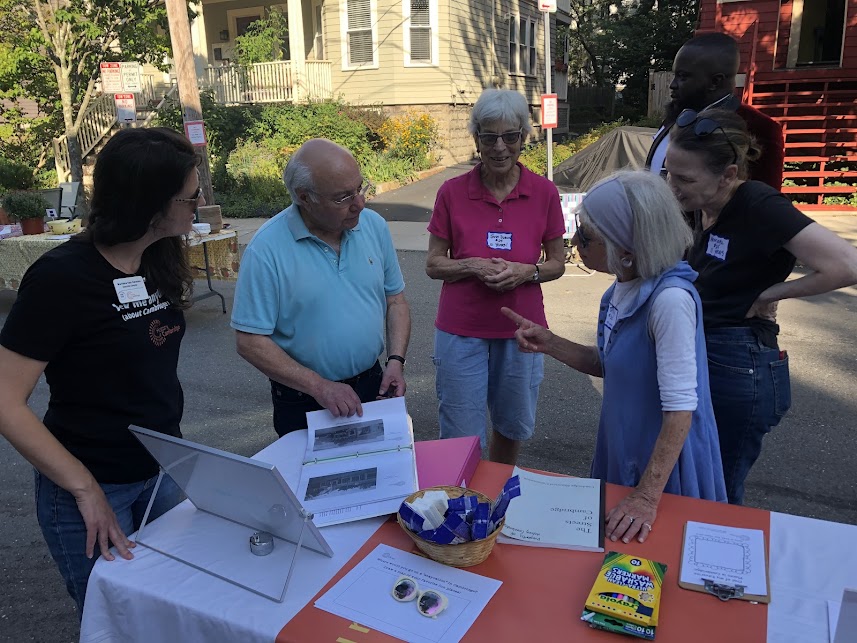 People gather around the History Kit table at a summer neighborhood block party.