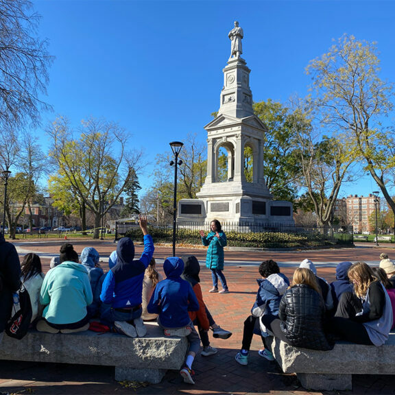 History Cambridge program manager Beth Folsom gives a tour of Cambridge Common monuments to students from BB&N Middle School.