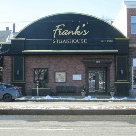 Street level view of a brick building with arched second floor that reads "Frank's Steakhouse"
